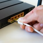Hand som kopplar in en nätverkskabel i en router