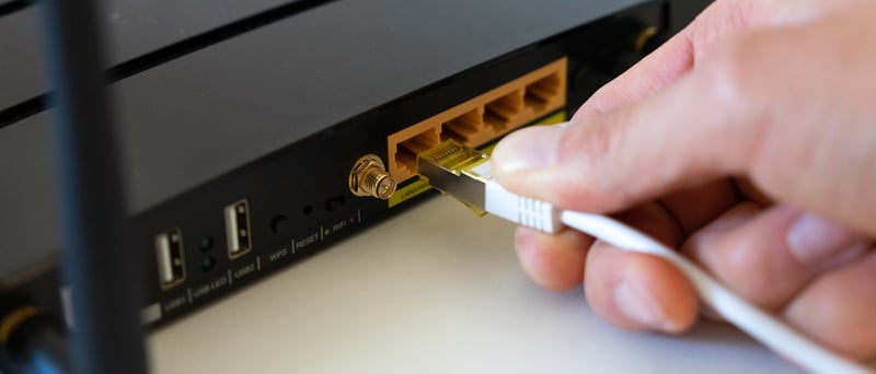 Hand som kopplar in en nätverkskabel i en router