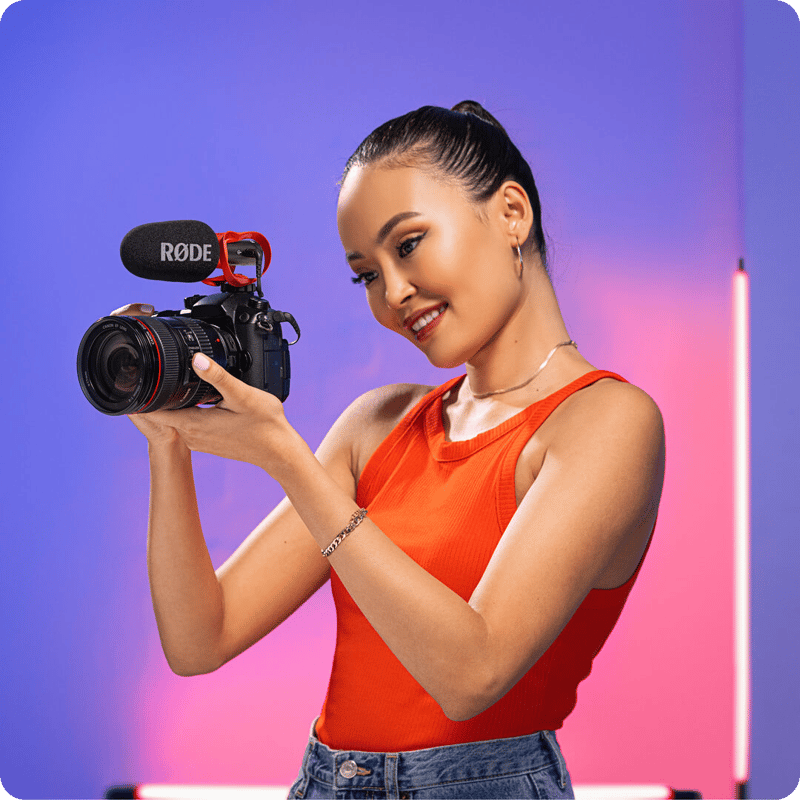 Kvinna håller en kamera med VideoMic GO II monterad
